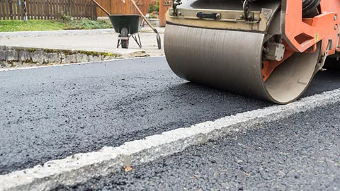Road roller compacting freshly laid tarmac